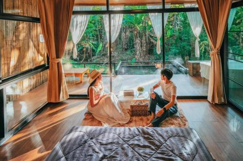 two people sitting in a room with a large window at ภูธารา กลางดง in Ban Thung Phan Ha