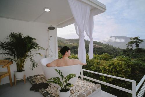 a man sitting in a bath tub on a balcony at ภูธารา กลางดง in Ban Thung Phan Ha
