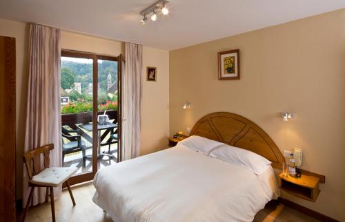 a bedroom with a bed and a balcony with a table at Hotel Au Vieux Moulin in Graufthal