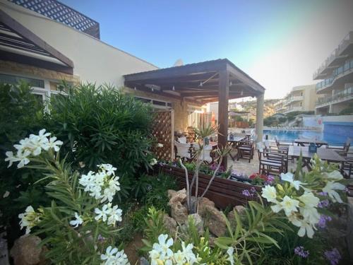 a garden with white flowers in front of a house at Luxury house Makry gialos 200m to the beach 6 pers in Makry Gialos