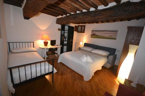 シエナにあるAppartamento del Campoのベッドルーム1室(ベッド2台、ランプ付きテーブル付)