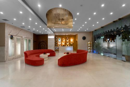 a lobby with two red chairs and a chandelier at Grand Plaza Lords Inn Jammu in Jammu