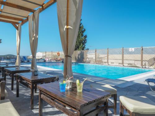 a patio with wooden tables and a swimming pool at Paleo ArtNouveau Hotel - Adults Only in Paleokastritsa