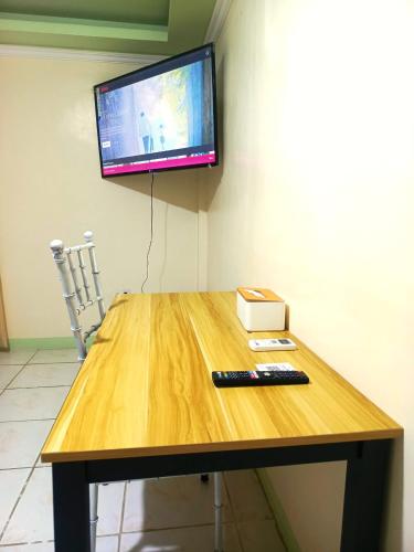 a wooden table with a television and a remote control on it at Legends Apartel in Lemery