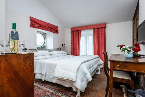 a bedroom with a large white bed and a table at Villa Acquaviva Wine Resort in Montemerano