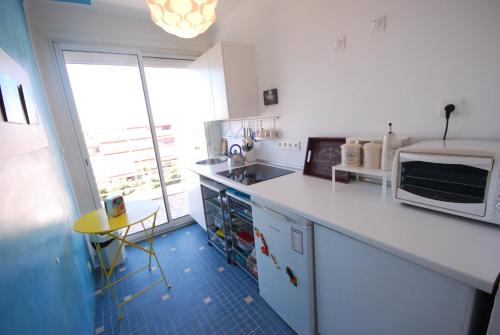 - une cuisine blanche avec un four micro-ondes et un évier dans l'établissement Palm Beach Appartement Proche Mer, à Cannes