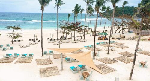 a beach with chairs and palm trees and the ocean at Gerbi's Condoplace at Oceanway Residences in Sampong