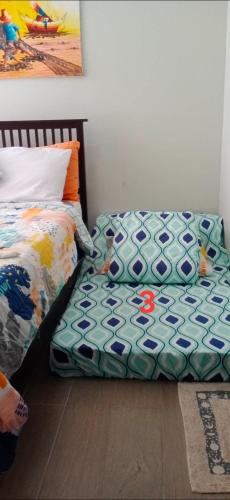 a bedroom with a bed and a comforter on the floor at Gerbi's Condoplace at Oceanway Residences in Sampong