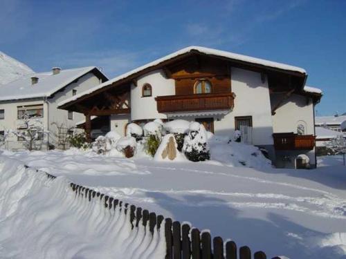 a house is covered in snow with a fence at Ferienwohnung Pangratz in Tarrenz