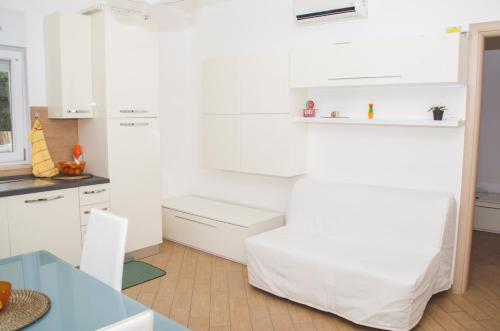 a white kitchen with a table and a white chair at Sun Garden l.t. in Fiumicino