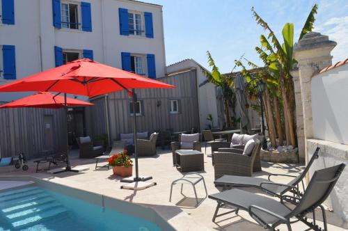 un patio avec des chaises et des parasols à côté d'une piscine dans l'établissement Hotel La Chaudrée, à La Brée-les-Bains