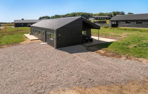 a small building with a black roof on a field at Beautiful Home In Haderslev With Sauna in Haderslev