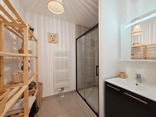 une salle de bain avec une douche en verre et un lavabo dans l'établissement l'Ecrin de Malo - Vue Mer, à Dunkerque