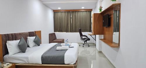 a bedroom with a bed with a desk and a television at Hotel 4 Season in Vadodara