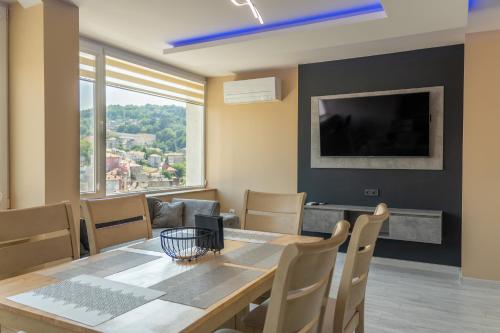 a dining room with a table and chairs and a television at Апартамент Балкан Тауър in Gabrovo