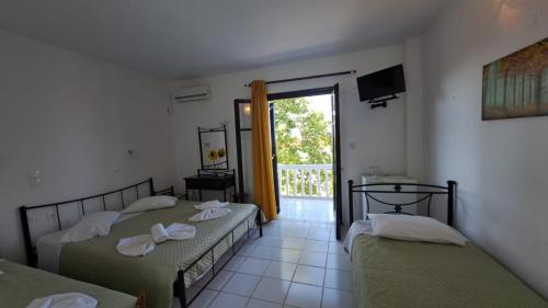 two beds in a room with a window at Kefalonia Beach Hotel & Bungalows in Lixouri