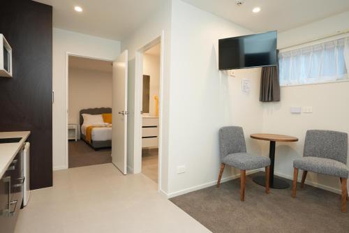 a room with a table and two chairs and a television at Airport Delight Motel in Auckland