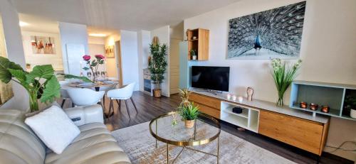 a living room with a white couch and a tv at LE DOMAINE DU GOLFE, Vue Exceptionnelle, Standing, 2 parkings, Climatisation, Piscine, Tennis in Sète