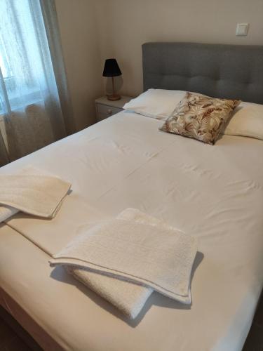 a bed with white sheets and two towels on it at Fotini's House in Ligourio