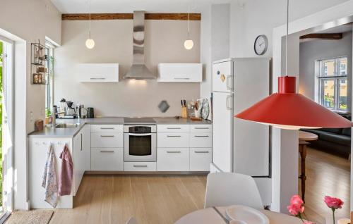 a kitchen with white cabinets and a red lamp at 3 Bedroom Awesome Home In Nysted in Nysted