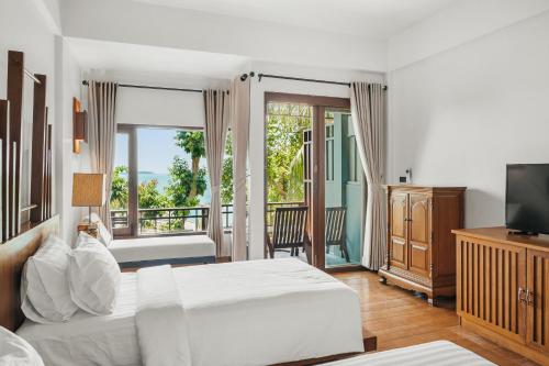 a bedroom with a bed and a television and a balcony at The Kala in Amphoe Koh Samui