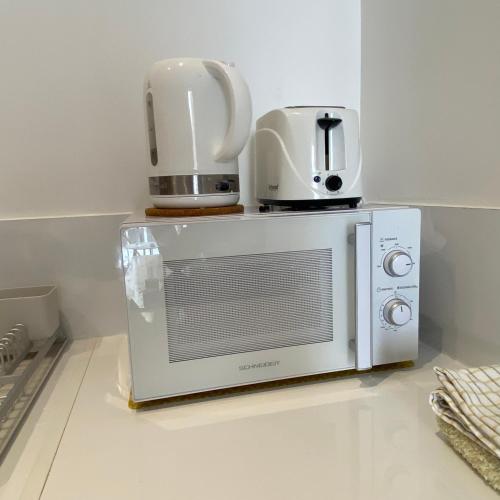 un micro-ondes avec deux tasses dessus dans l'établissement Belle chambre d hôte Et cuisine hyper centre, à Bastia