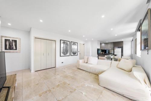 a living room with a white couch and a kitchen at 3Bds& FishM &Citylife Super Cozy in Sydney