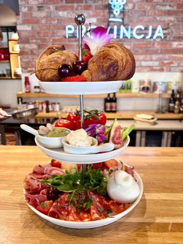 a three tiered plate of food on a table at Boutique Provincja Winebar & Rooms in Olsztyn