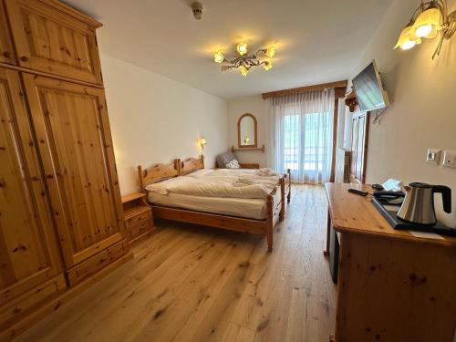 a bedroom with a bed and a desk in a room at Hotel Arnika Wellness in Passo San Pellegrino
