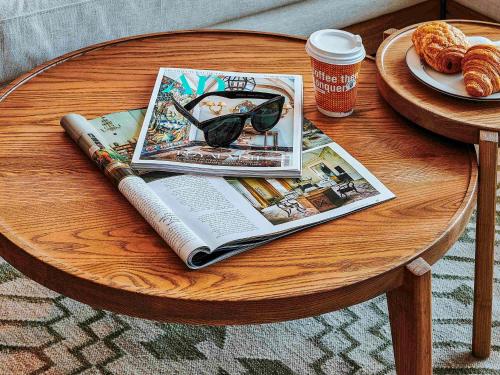 a table with a magazine and a book and a cup of coffee at 25hours Hotel Dubai One Central in Dubai