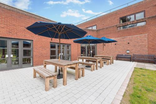 a group of picnic tables and umbrellas in front of a building at Lilleshall House & Gardens and Lilleshall National Sports Centre in Telford