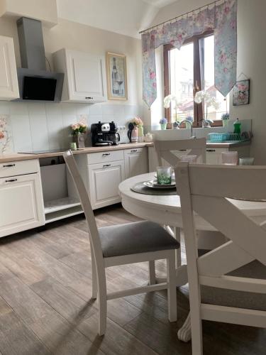 a kitchen with white cabinets and a table and chairs at Rubinowe Apartamenty in Sandomierz