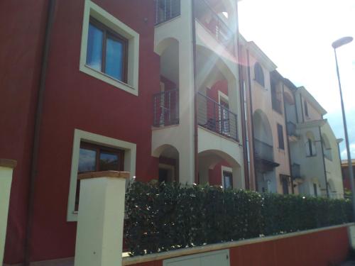 a red building with a hedge in front of it at Entula in Àrbatax