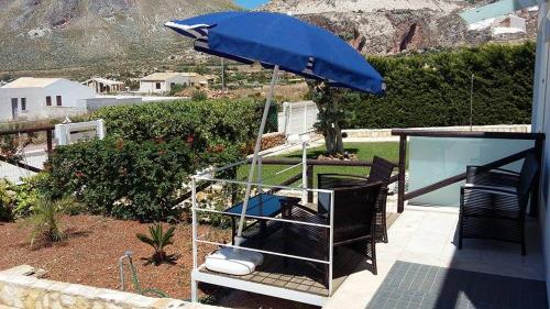 a patio with a blue umbrella and chairs and a table at Case Vacanza Viola di Mare in Custonaci