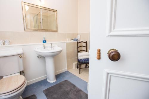 uma casa de banho com um WC, um lavatório e um espelho. em Holly Lodge em Strathpeffer