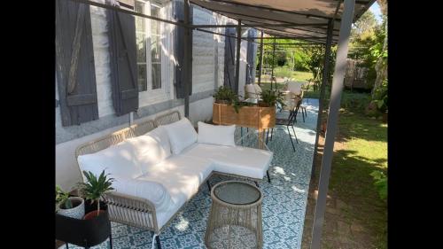 a porch with a white couch and a table at Gîte avec jacuzzi privatif à proximité de l'océan in Saint-Julien-en-Born