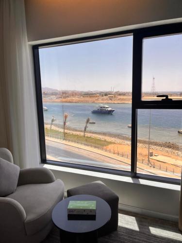 a living room with a large window with a boat in the water at شقق همس البحر Hams Apartments in Ḑubā