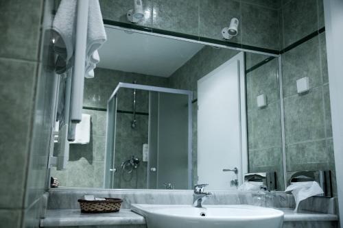a bathroom with a sink and a shower and a mirror at Hotel Bellevue in Skopje