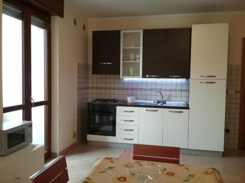 een keuken met witte kasten, een wastafel en een tafel bij Sunny in Lecce