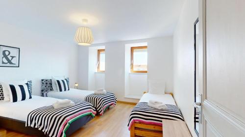 deux lits dans une chambre aux murs blancs et au parquet dans l'établissement Les Cordonniers, à Colmar