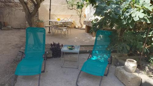 2 chaises bleues et une table dans un jardin dans l'établissement La maison de jeanne, à Vauvert