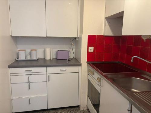 a kitchen with white cabinets and a sink and red tiles at Bern str 140 in Ostermundigen