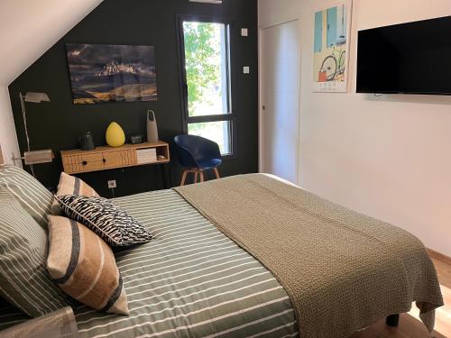a bedroom with a bed and a desk and a window at Chambre du mont saint Michel in Bacilly