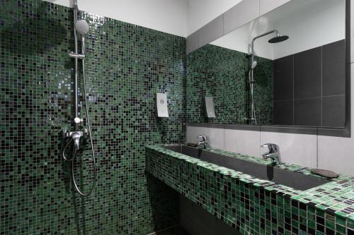 a green tiled bathroom with a shower and a sink at Boutique Hôtel Entraigues in Uzès