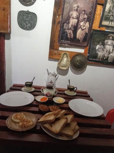 a wooden table with plates of food on it at The Paulwood cabana home stay in Nuwara Eliya