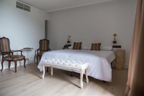 a bedroom with a white bed with two chairs and a table at Granxa D Outeiro in Ribadavia