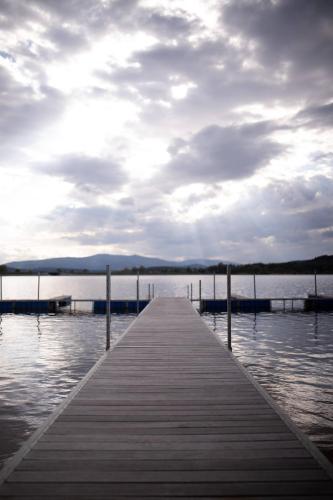 a dock on a body of water with a cloudy sky at Apartmán se soukromou zahradou u břehu Lipna in Černá v Pošumaví