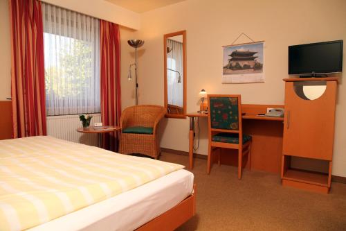 a hotel room with a bed and a desk and a television at Hotel Paulsen in Zeven