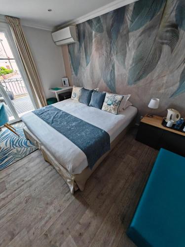 a bedroom with a bed with a painting on the wall at Boutique Hôtel de la Corniche d'Or in Mandelieu-la-Napoule