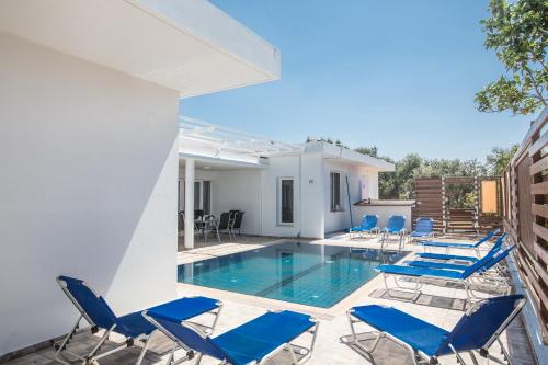 a swimming pool with blue chairs and a house at Napa Nissi House in Ayia Napa